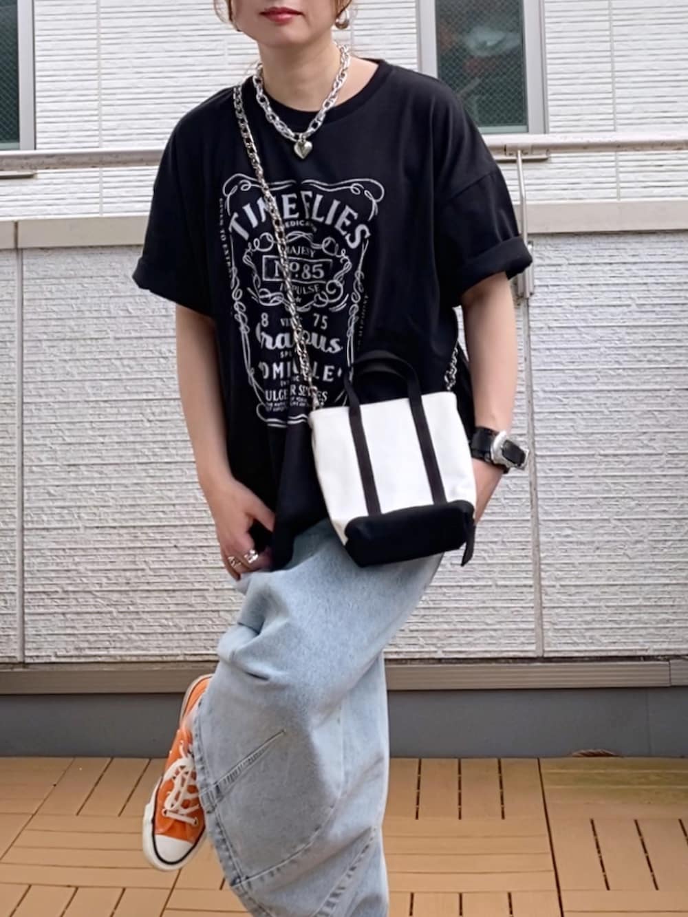 ブラック系のTシャツ/カットソー、ブルー系のデニムスカート、オレンジ系のスニーカーを着用したレディースの夏コーディネートの3枚目の写真