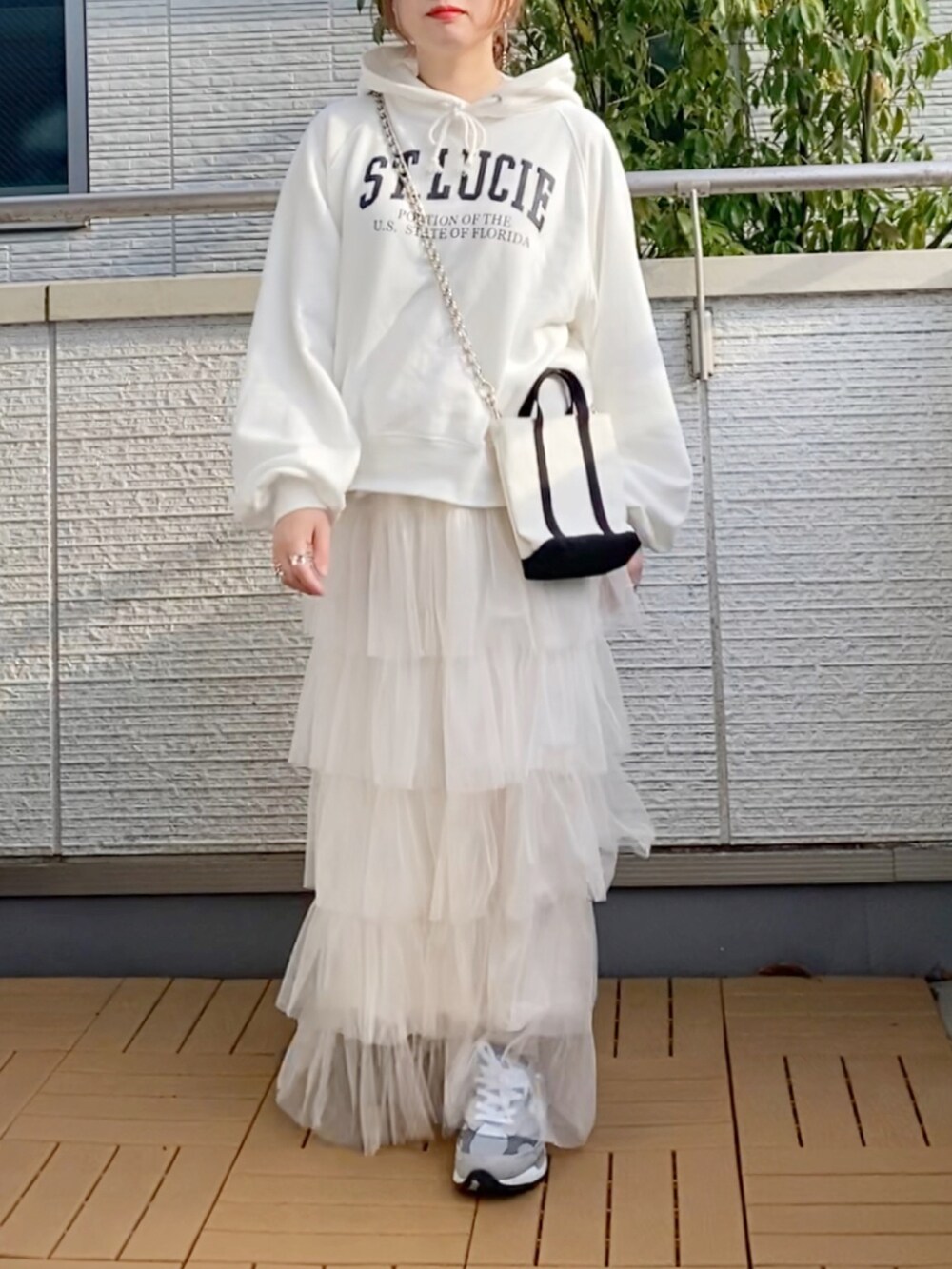 ホワイト系のパーカー、ホワイト系のスカート、グレー系のスニーカーを着用したレディースの春コーディネートの2枚目の写真