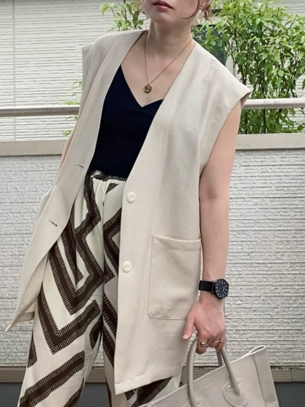 ブラック系のキャミソール、ベージュ系のベスト、ホワイト系のその他パンツを着用したレディースの夏コーディネートの2枚目の写真