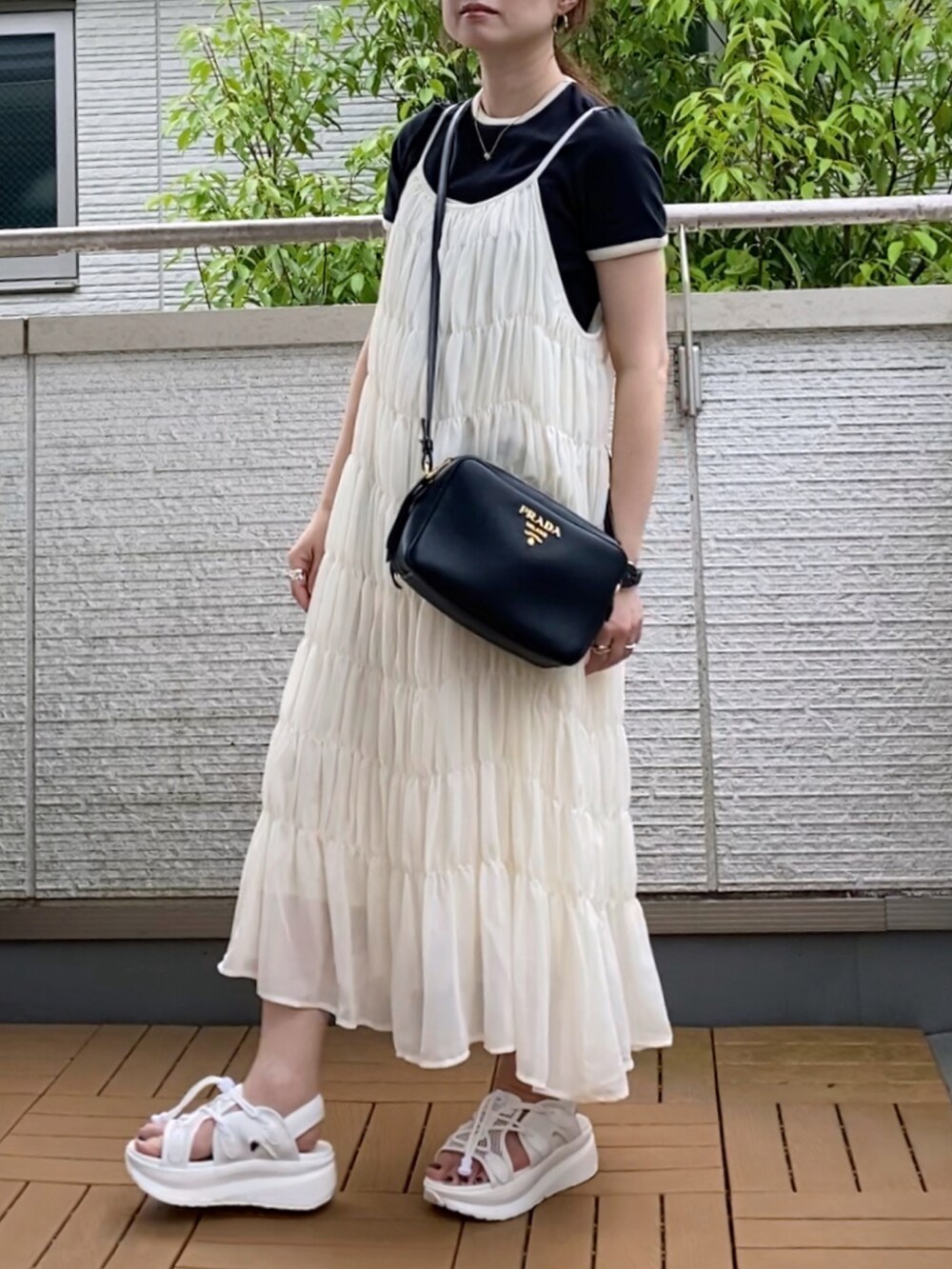 ホワイト系のワンピース、ブラック系のTシャツ/カットソー、ホワイト系のサンダルを着用したレディースの夏コーディネートの2枚目の写真