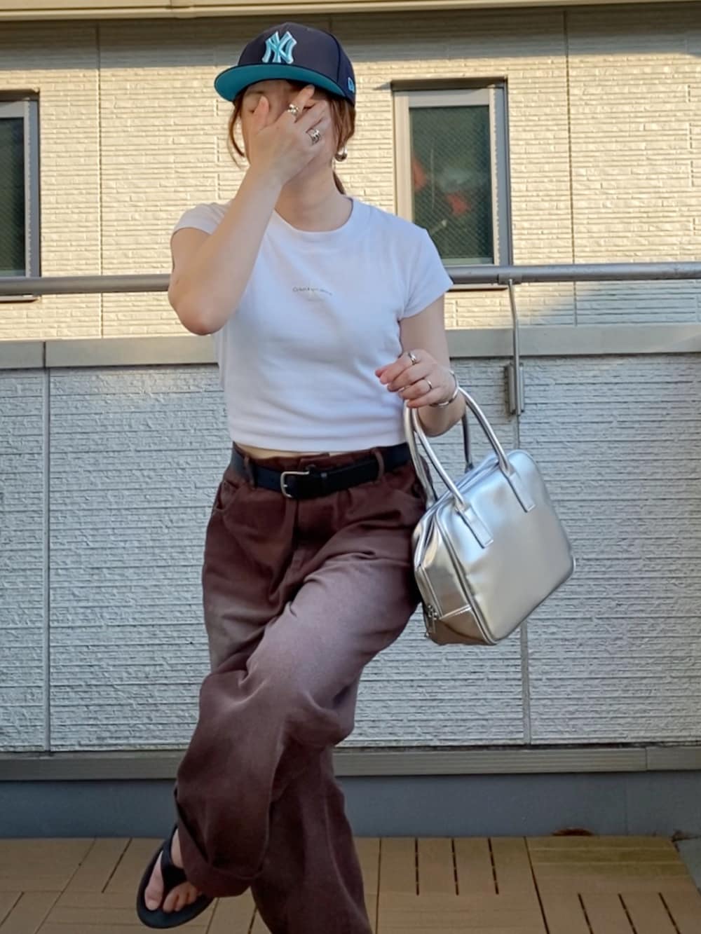 ホワイト系のTシャツ/カットソー、ブラウン系のデニムパンツ、シルバー系のボストンバッグを着用したレディースの夏コーディネートの3枚目の写真