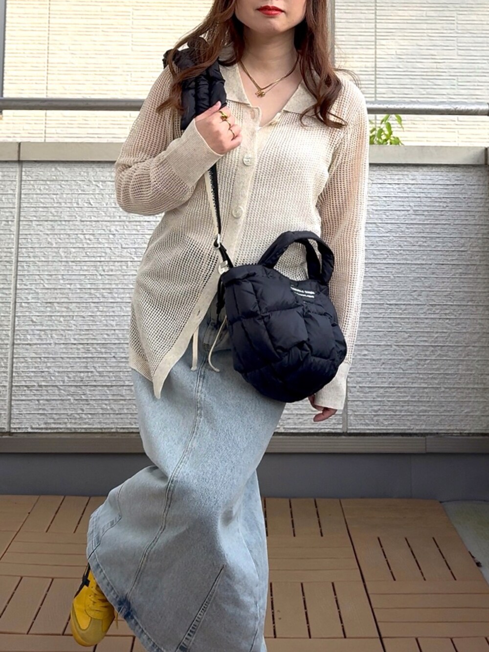 ベージュ系のカーディガン/ボレロ、ブルー系のデニムスカート、ブラック系のショルダーバッグを着用したレディースの春コーディネートの4枚目の写真