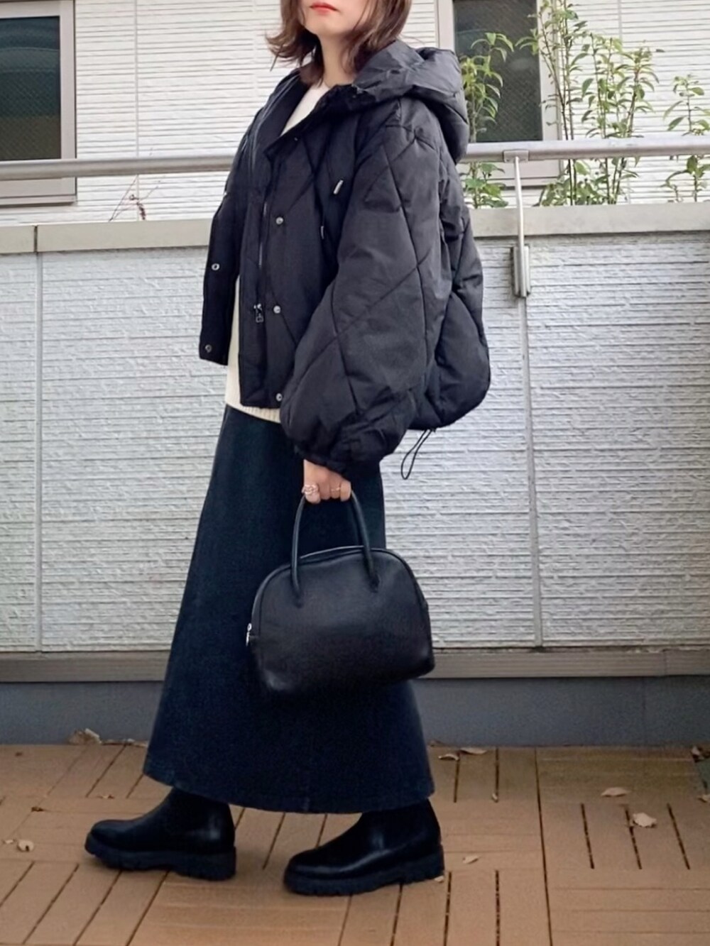 ブラック系のダウンジャケット/コート、ブラック系のスカート、ブラック系のショルダーバッグを着用したレディースの秋コーディネートの3枚目の写真