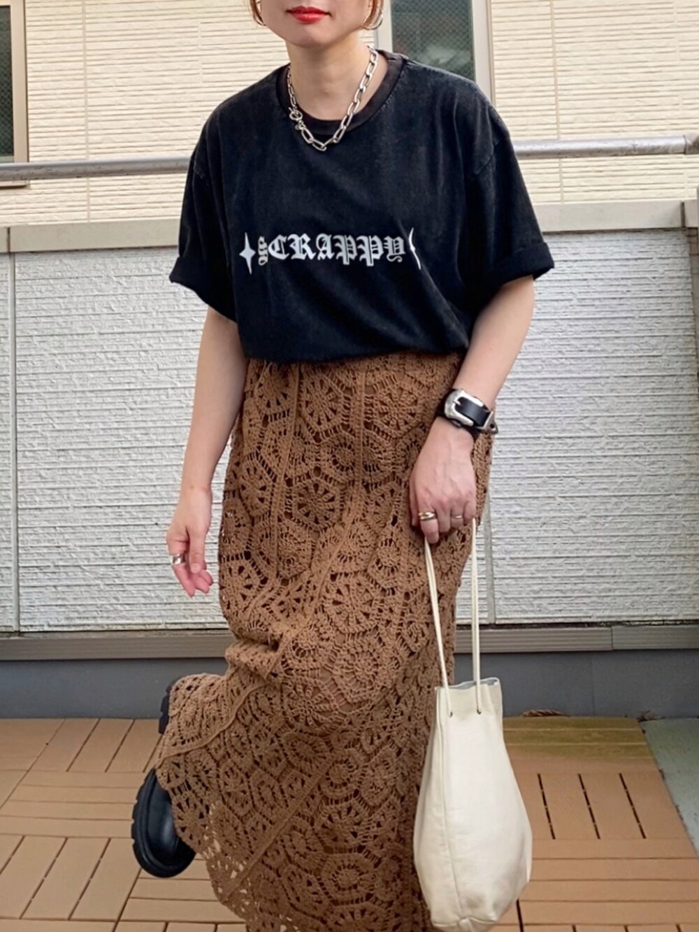 ブラック系のTシャツ/カットソー、ブラウン系のスカート、ブラック系のブーツを着用したレディースの秋コーディネートの3枚目の写真