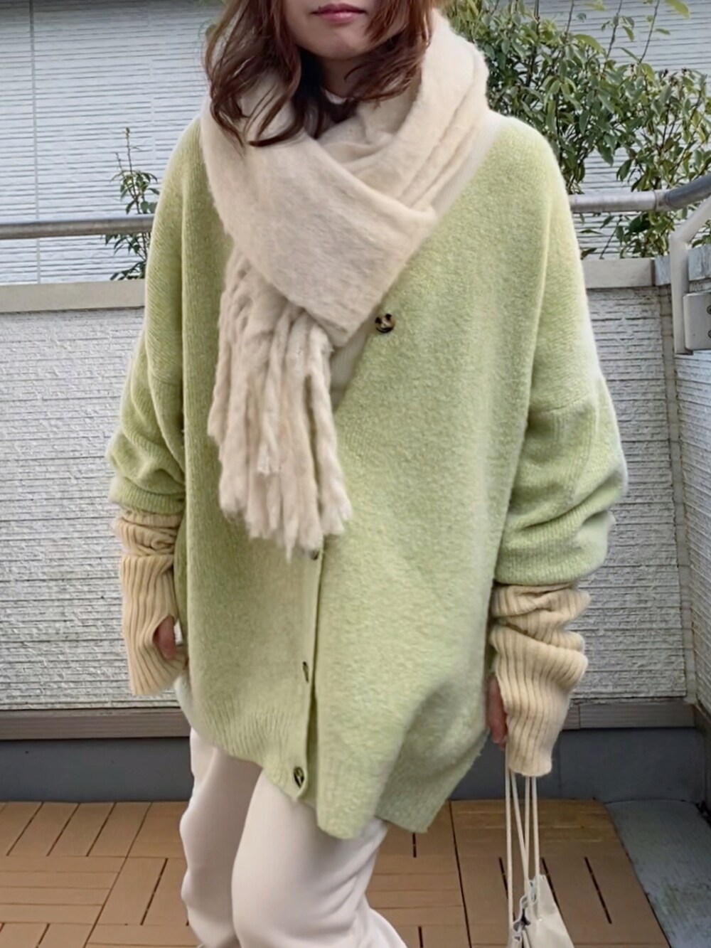 グリーン系のカーディガン/ボレロ、ホワイト系のパンツ、ホワイト系のショルダーバッグを着用したレディースの冬コーディネートの2枚目の写真