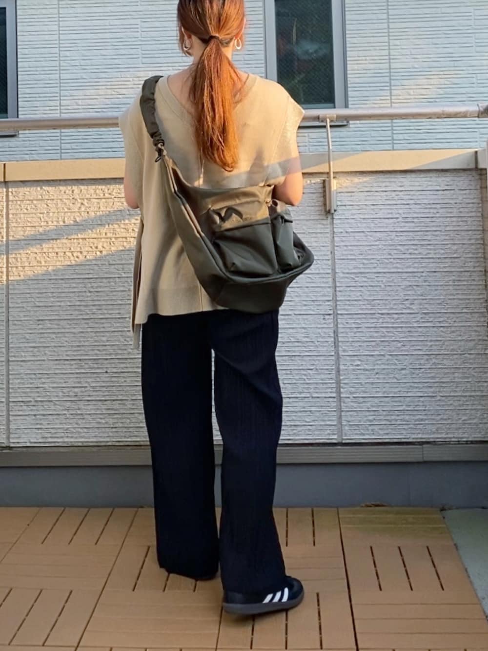 ベージュ系のニット/セーター、ブラック系のその他パンツ、グリーン系のショルダーバッグを着用したレディースの秋コーディネートの4枚目の写真