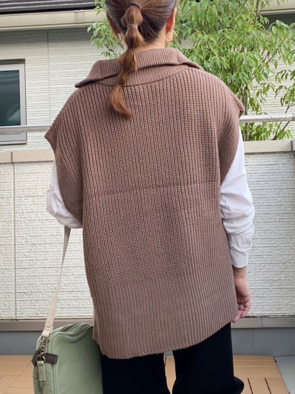 ブラウン系のベスト、ブラック系のデニムパンツ、グリーン系のショルダーバッグを着用したレディースの秋コーディネートの4枚目の写真