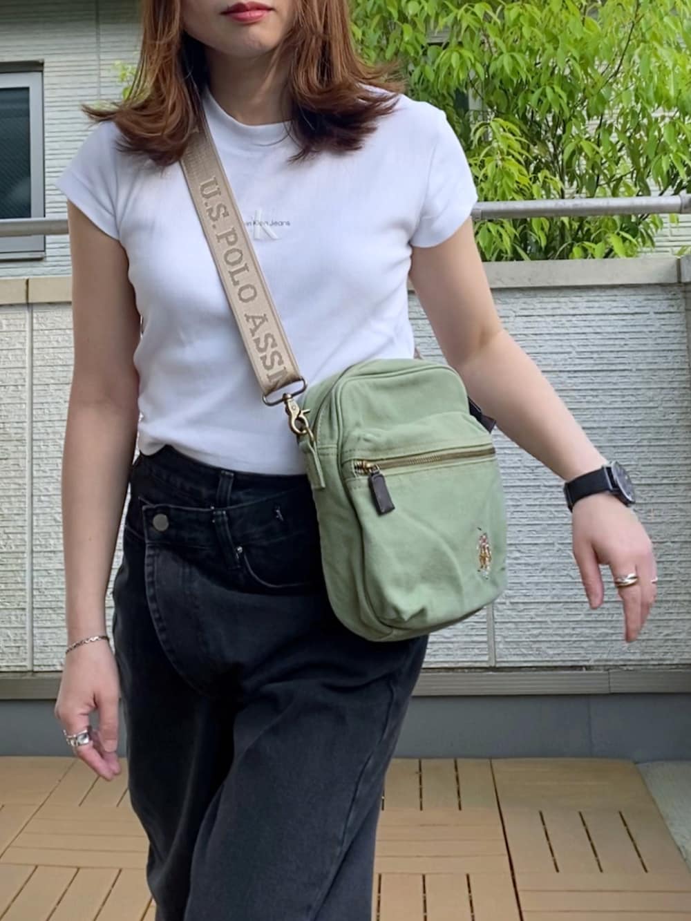 ホワイト系のTシャツ/カットソー、ブラック系のデニムパンツ、グリーン系のショルダーバッグを着用したレディースの春コーディネートの2枚目の写真