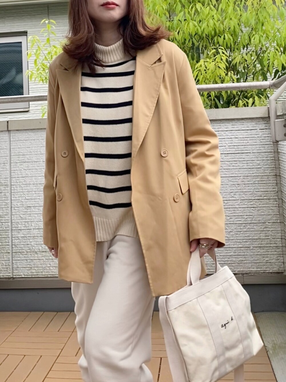 ベージュ系のテーラードジャケット、ホワイト系のニット/セーター、ホワイト系のパンツを着用したレディースの春コーディネートの2枚目の写真