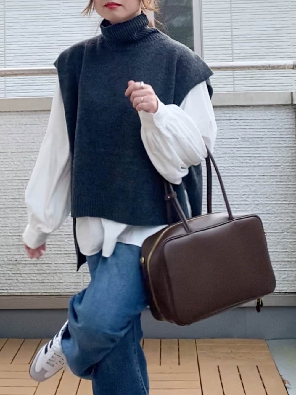 グレー系のベスト、ホワイト系のシャツ/ブラウス、ブルー系のデニムパンツを着用したレディースの冬コーディネートの5枚目の写真