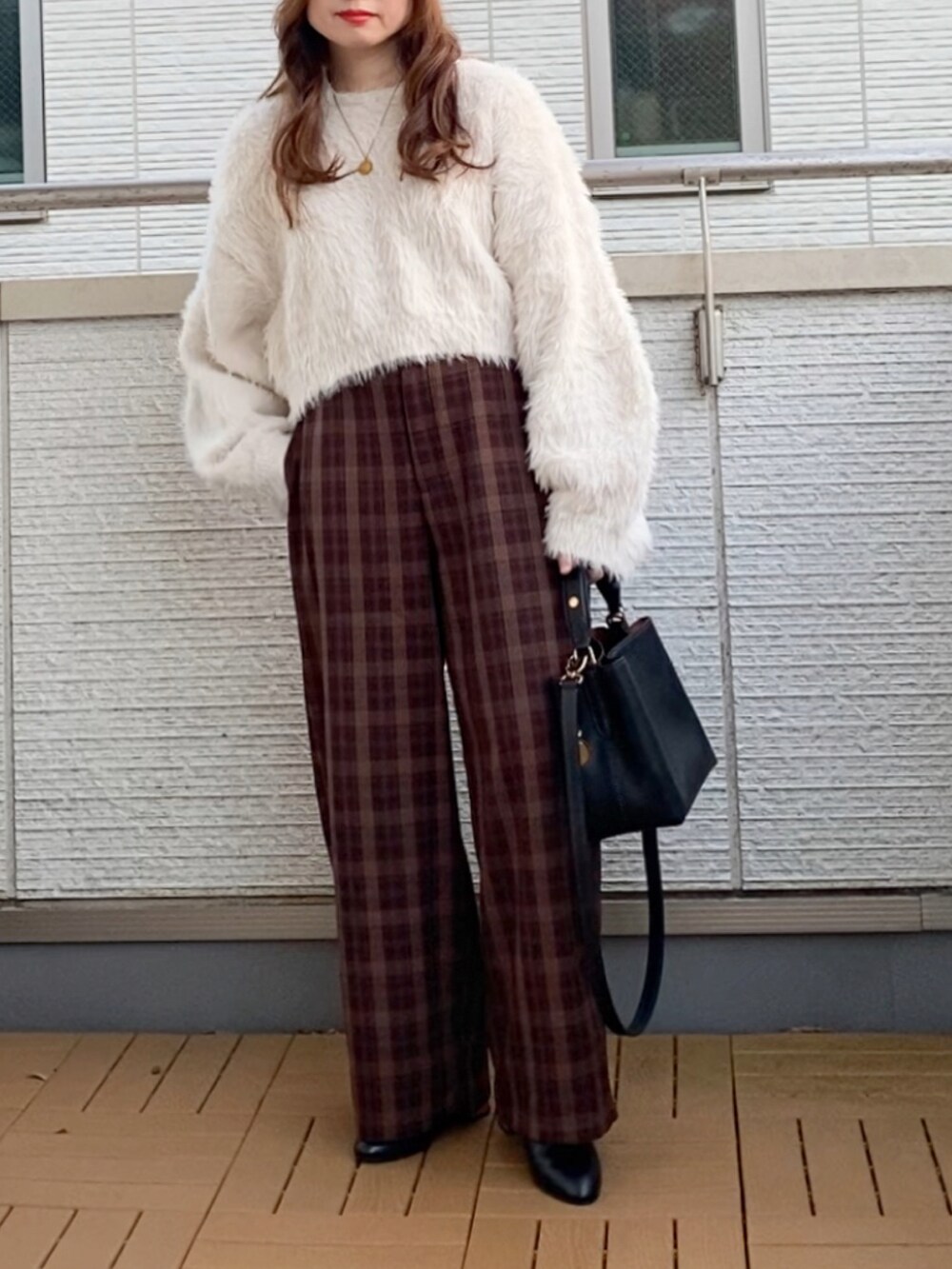 ホワイト系のニット/セーター、ブラウン系のその他パンツ、ブラック系のショルダーバッグを着用したレディースの冬コーディネートの2枚目の写真
