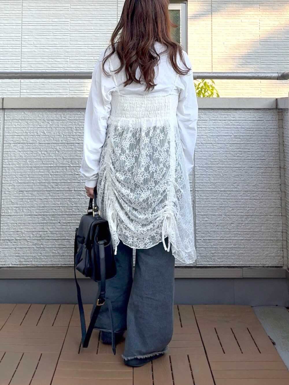 ホワイト系のワンピース、ブルー系のデニムパンツ、ブラック系のハンドバッグを着用したレディースの春コーディネートの4枚目の写真