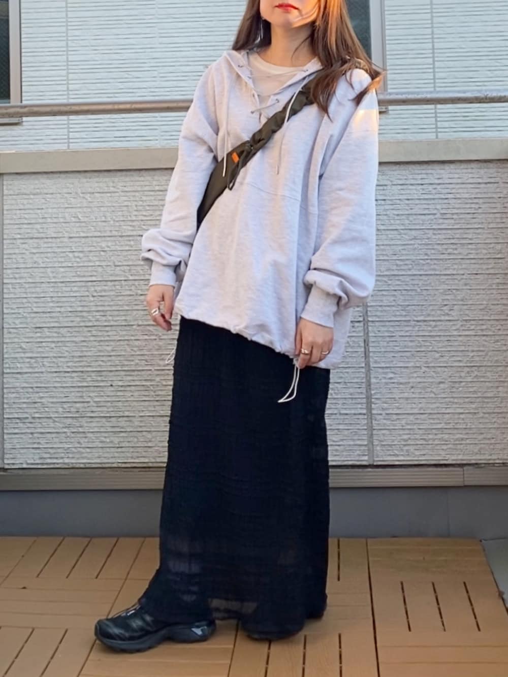 グレー系のパーカー、ブラック系のスカート、グリーン系のショルダーバッグを着用したレディースの冬コーディネートの2枚目の写真