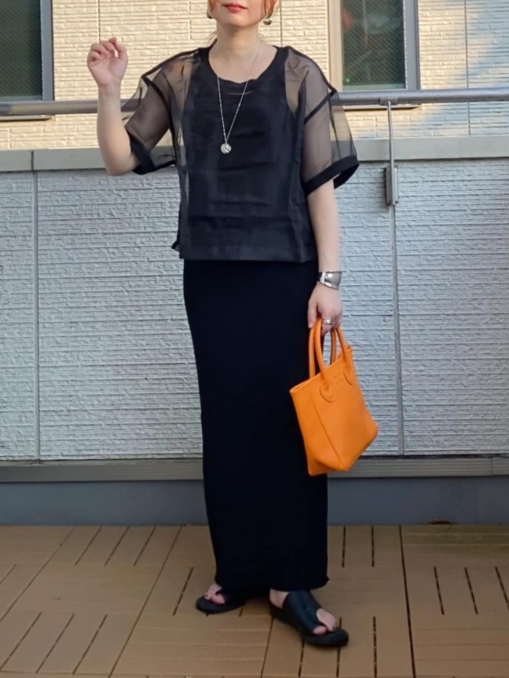 ブラック系のワンピース、ブラック系のTシャツ/カットソー、オレンジ系のトートバッグを着用したレディースの夏コーディネートの2枚目の写真