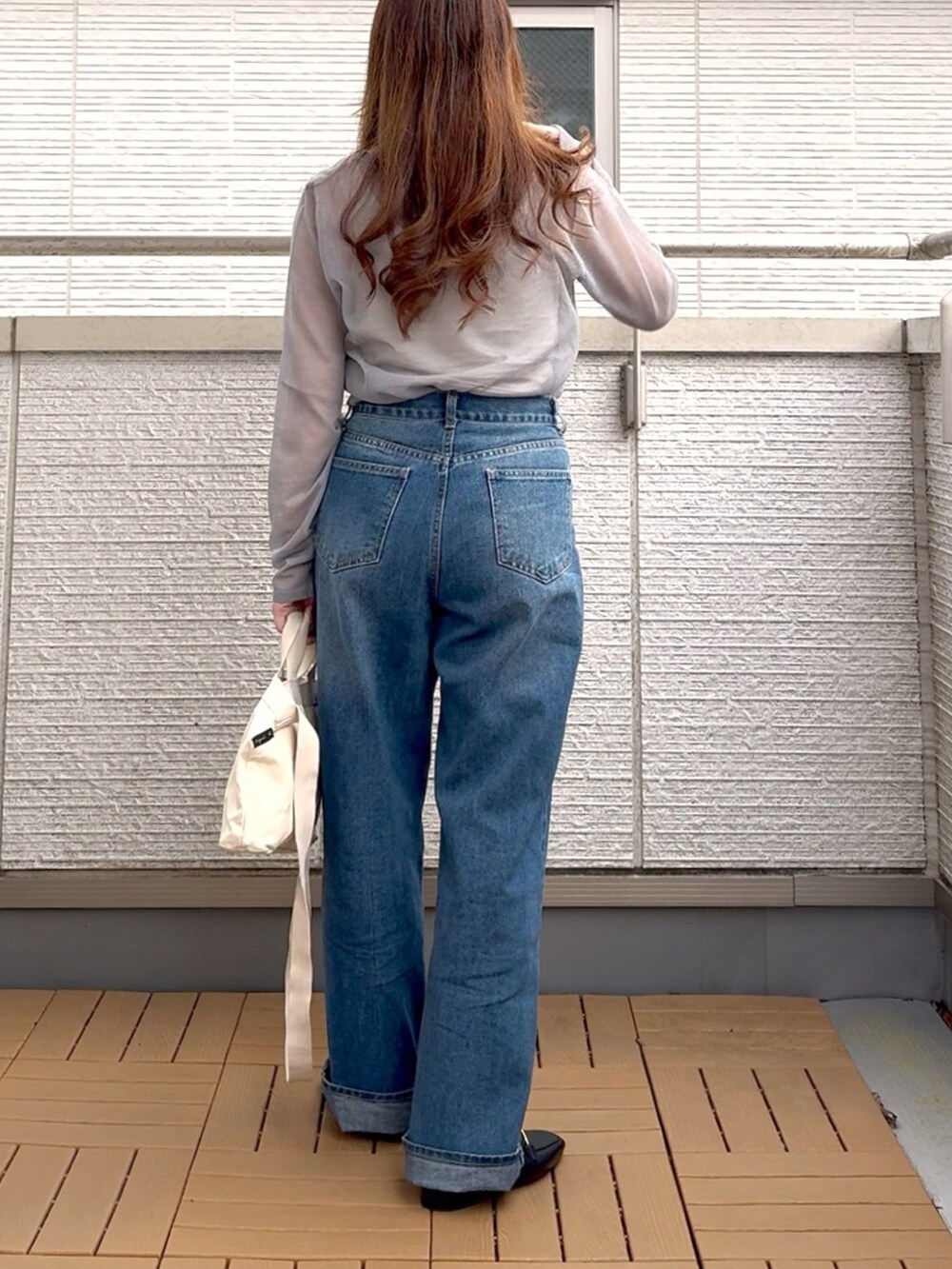 グレー系のニット/セーター、ブルー系のデニムパンツ、ホワイト系のトートバッグを着用したレディースの春コーディネートの4枚目の写真