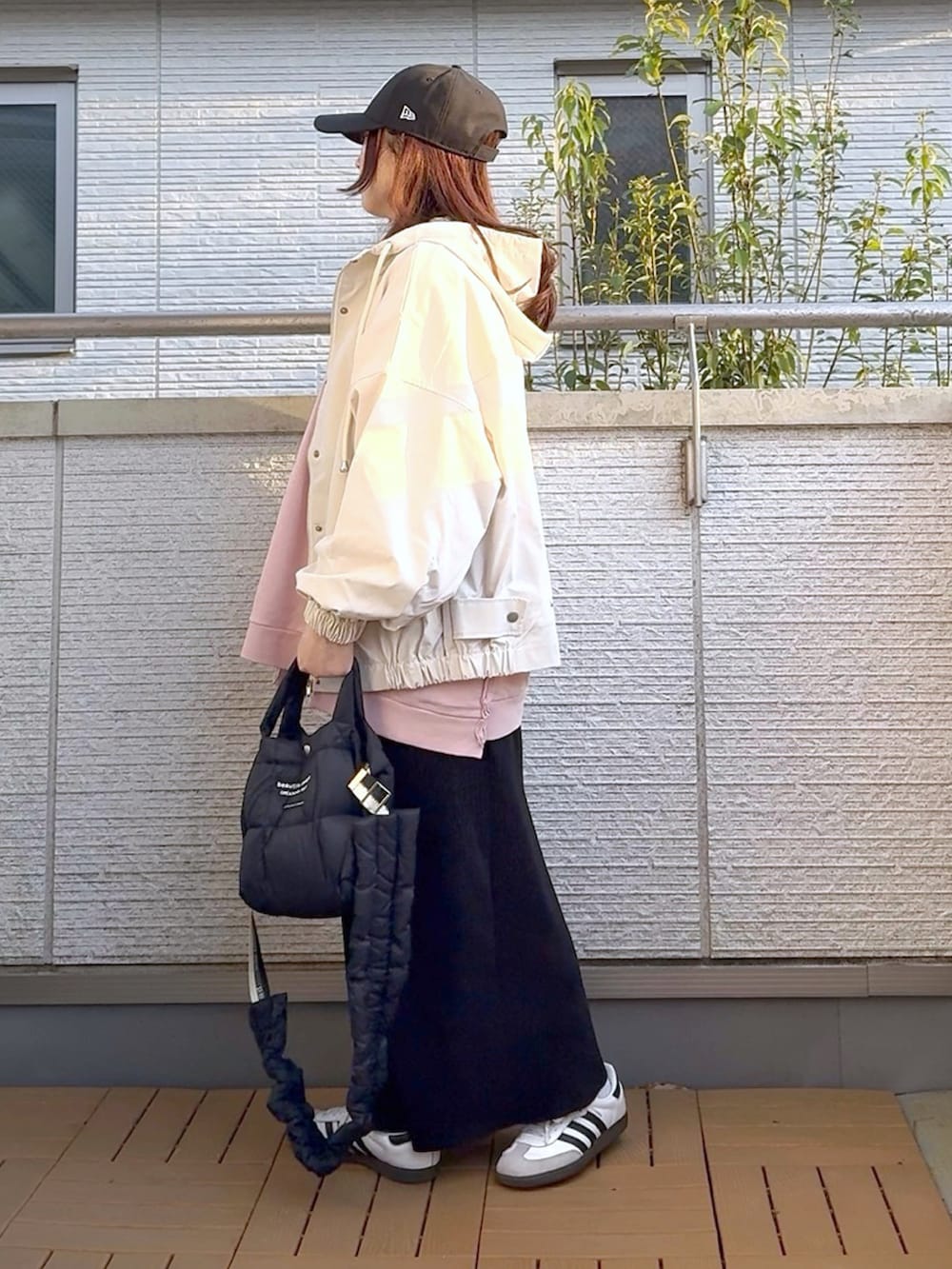 ピンク系のスウェット、ホワイト系のマウンテンパーカー、ブラック系のスカートを着用したレディースの春コーディネートの2枚目の写真