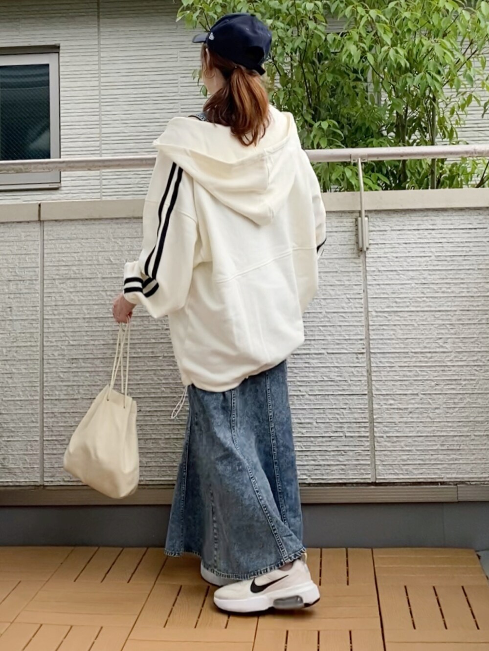 ホワイト系のパーカー、ブルー系のジャンパースカート、ホワイト系のスニーカーを着用したレディースの秋コーディネートの3枚目の写真