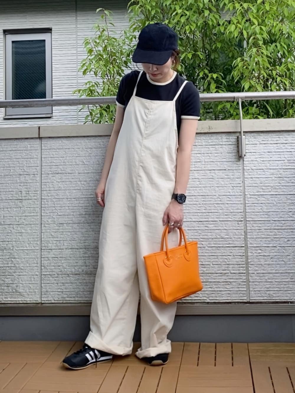 ホワイト系のサロペット/オーバーオール、ブラック系のTシャツ/カットソー、オレンジ系のトートバッグを着用したレディースの夏コーディネートの2枚目の写真