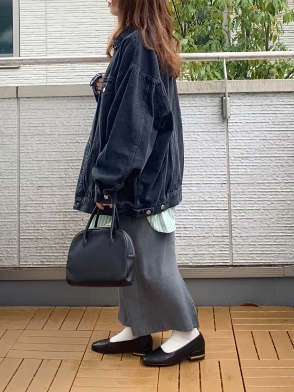 ブラック系のデニムジャケット、グリーン系のシャツ/ブラウス、グレー系のスカートを着用したレディースの春コーディネートの3枚目の写真