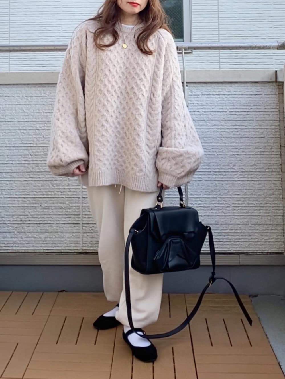 ベージュ系のニット/セーター、ホワイト系のパンツ、ブラック系のハンドバッグを着用したレディースの秋コーディネートの2枚目の写真