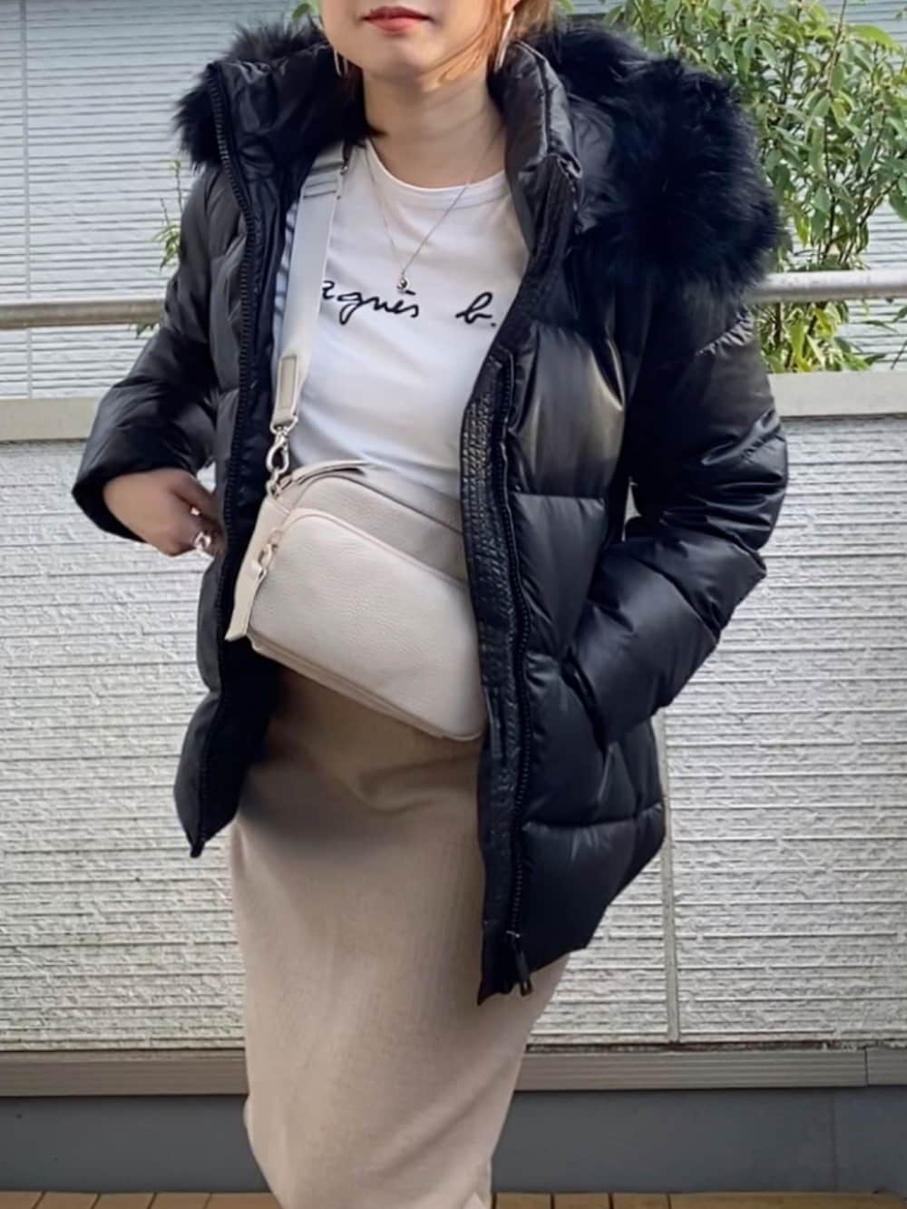 ブラック系のダウンジャケット/コート、ベージュ系のスカート、ブラウン系のショルダーバッグを着用したレディースの秋コーディネートの2枚目の写真