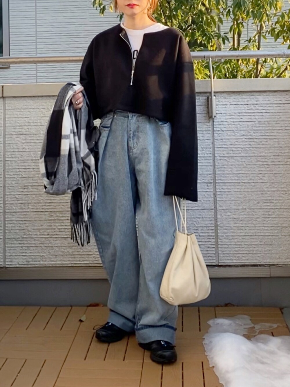 ブラック系のワンピース、ブルー系のデニムパンツ、ブラック系のスニーカーを着用したレディースの冬コーディネートの4枚目の写真