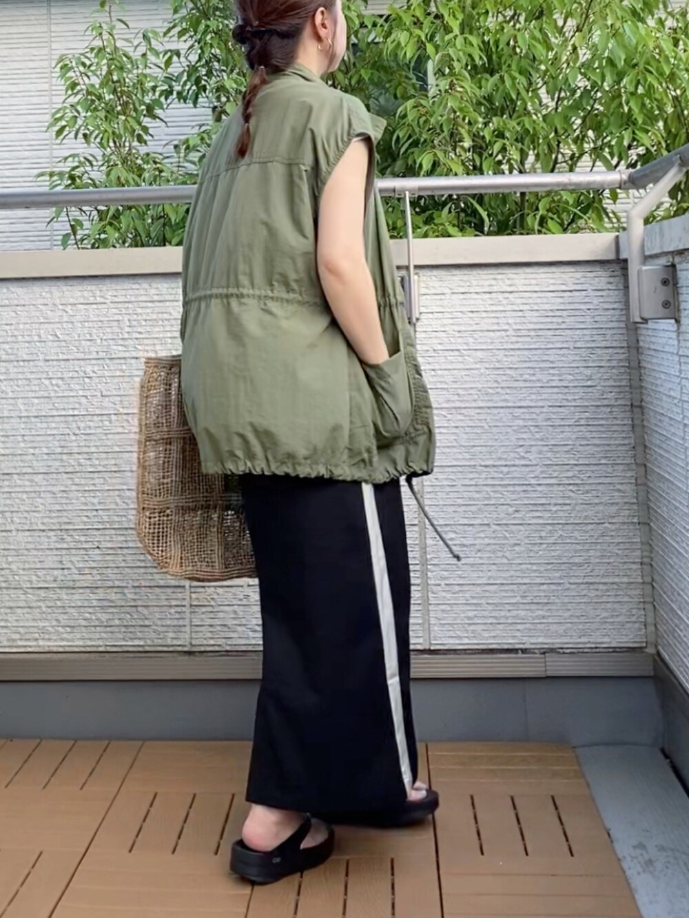 グリーン系のベスト、ホワイト系のTシャツ/カットソー、ブラック系のスカートを着用したレディースの夏コーディネートの3枚目の写真