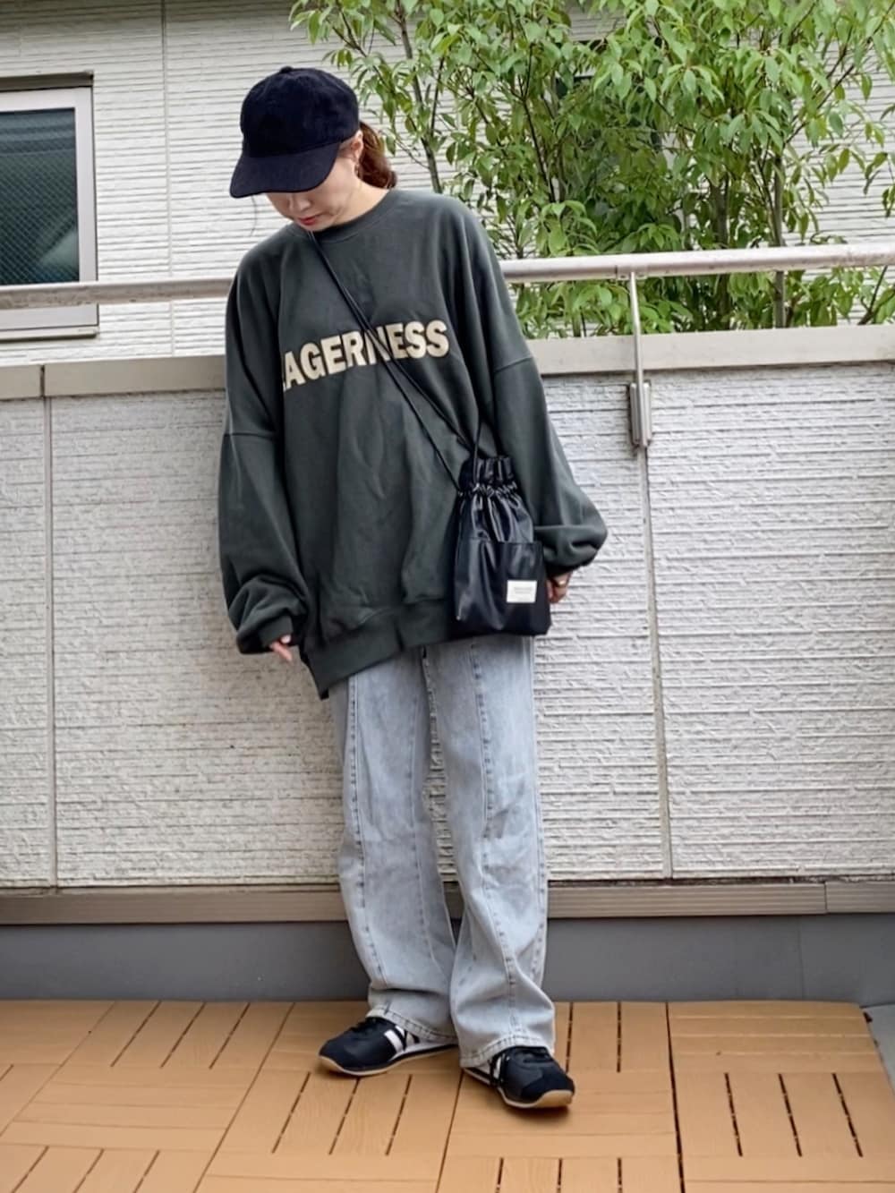 グリーン系のスウェット、ブルー系のデニムパンツ、ブラック系のショルダーバッグを着用したレディースの秋コーディネートの2枚目の写真