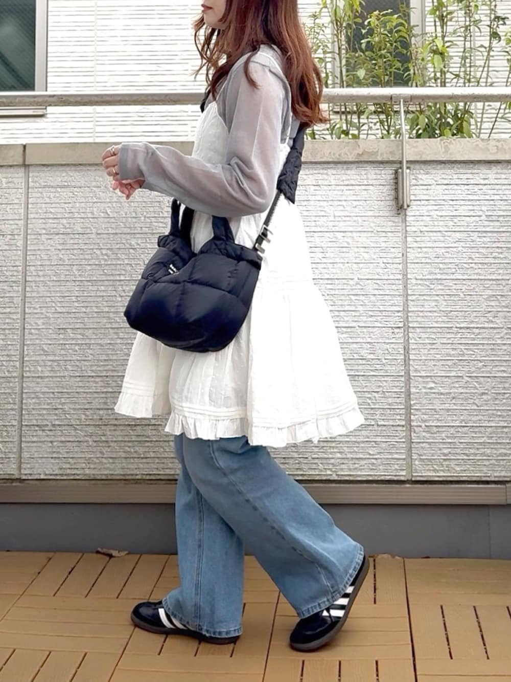 ホワイト系のワンピース、ブルー系のデニムパンツ、ブラック系のスニーカーを着用したレディースの春コーディネートの2枚目の写真