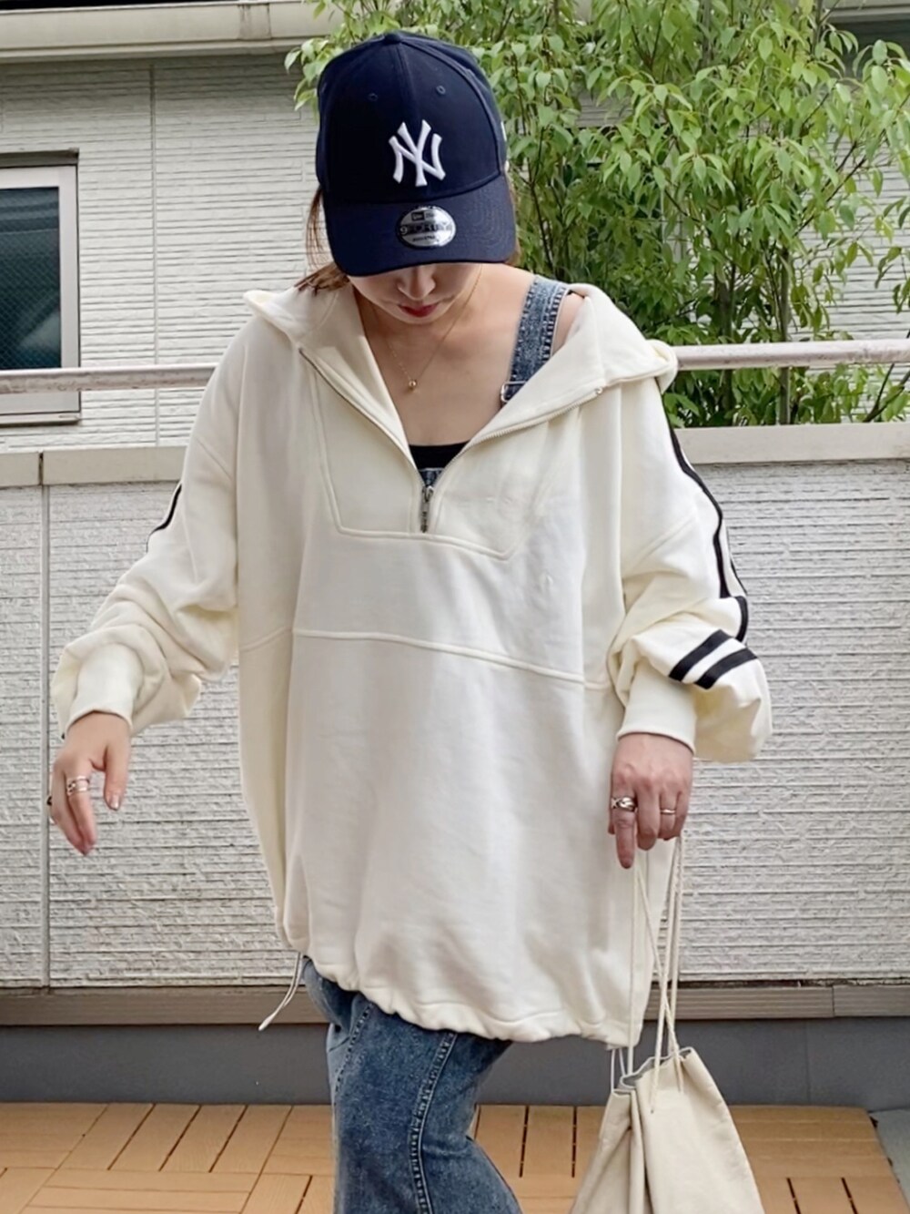 ホワイト系のパーカー、ブルー系のジャンパースカート、ホワイト系のスニーカーを着用したレディースの秋コーディネートの2枚目の写真