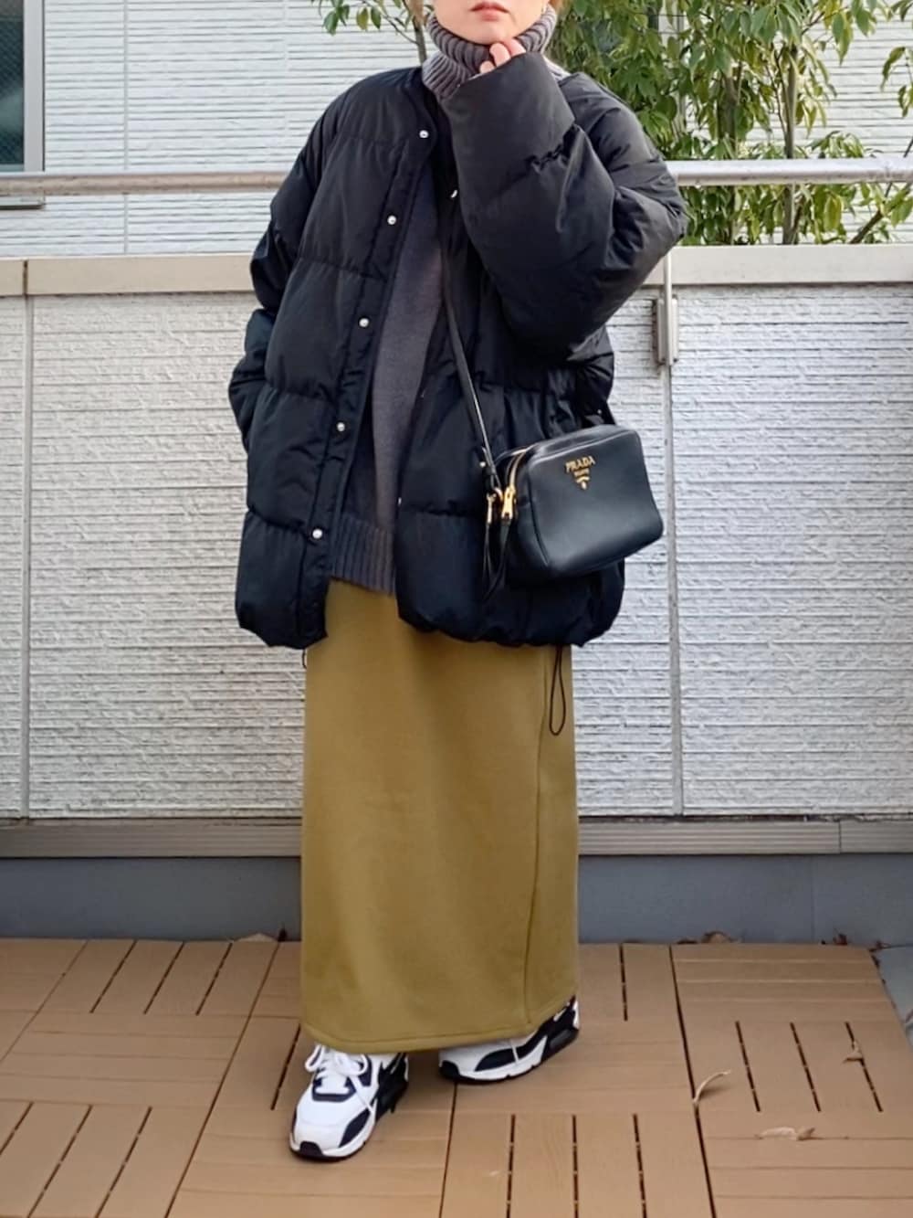 ブラック系のダウンジャケット/コート、グレー系のニット/セーター、グリーン系のスカートを着用したレディースの冬コーディネートの2枚目の写真