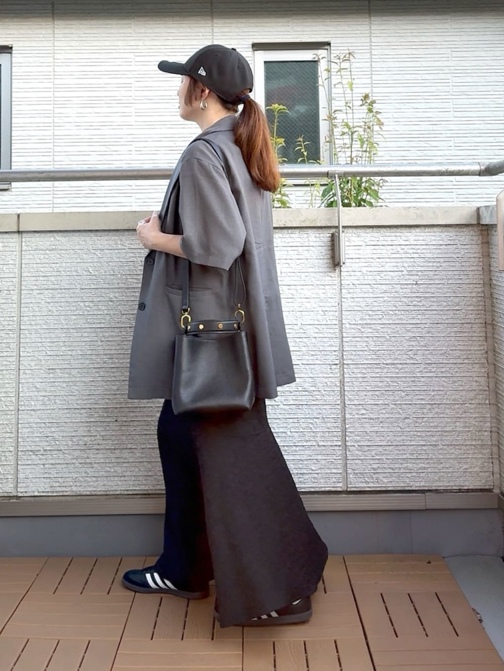 グレー系のテーラードジャケット、ブラック系のワンピース、ブラック系のショルダーバッグを着用したレディースの夏コーディネートの3枚目の写真