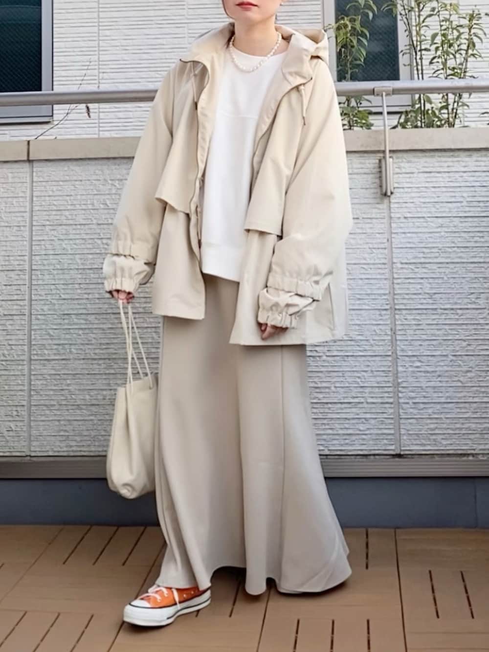 ホワイト系のモッズコート、ベージュ系のスカート、ホワイト系のショルダーバッグを着用したレディースの春コーディネートの2枚目の写真