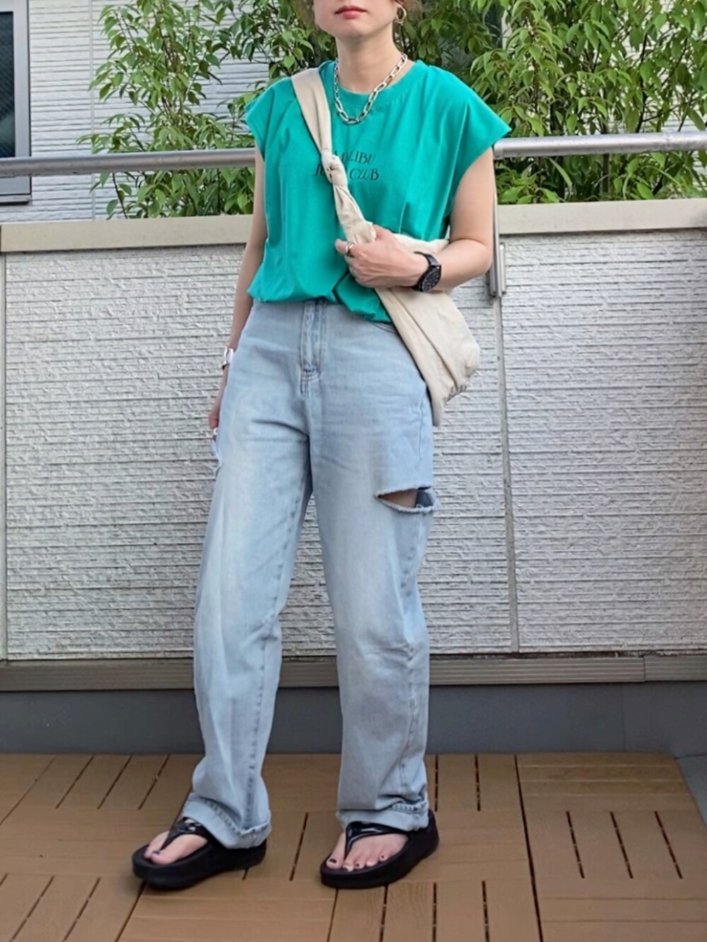 グリーン系のTシャツ/カットソー、ブルー系のデニムパンツ、ホワイト系のショルダーバッグを着用したレディースの夏コーディネートの2枚目の写真