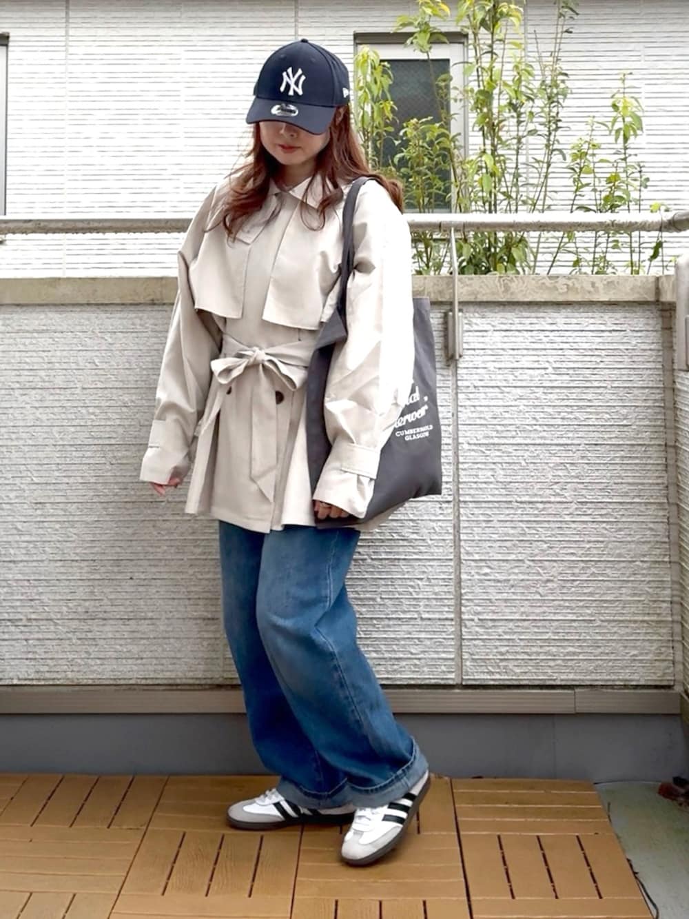 ホワイト系のトレンチコート、ブルー系のデニムパンツ、ホワイト系のスニーカーを着用したレディースの春コーディネートの2枚目の写真