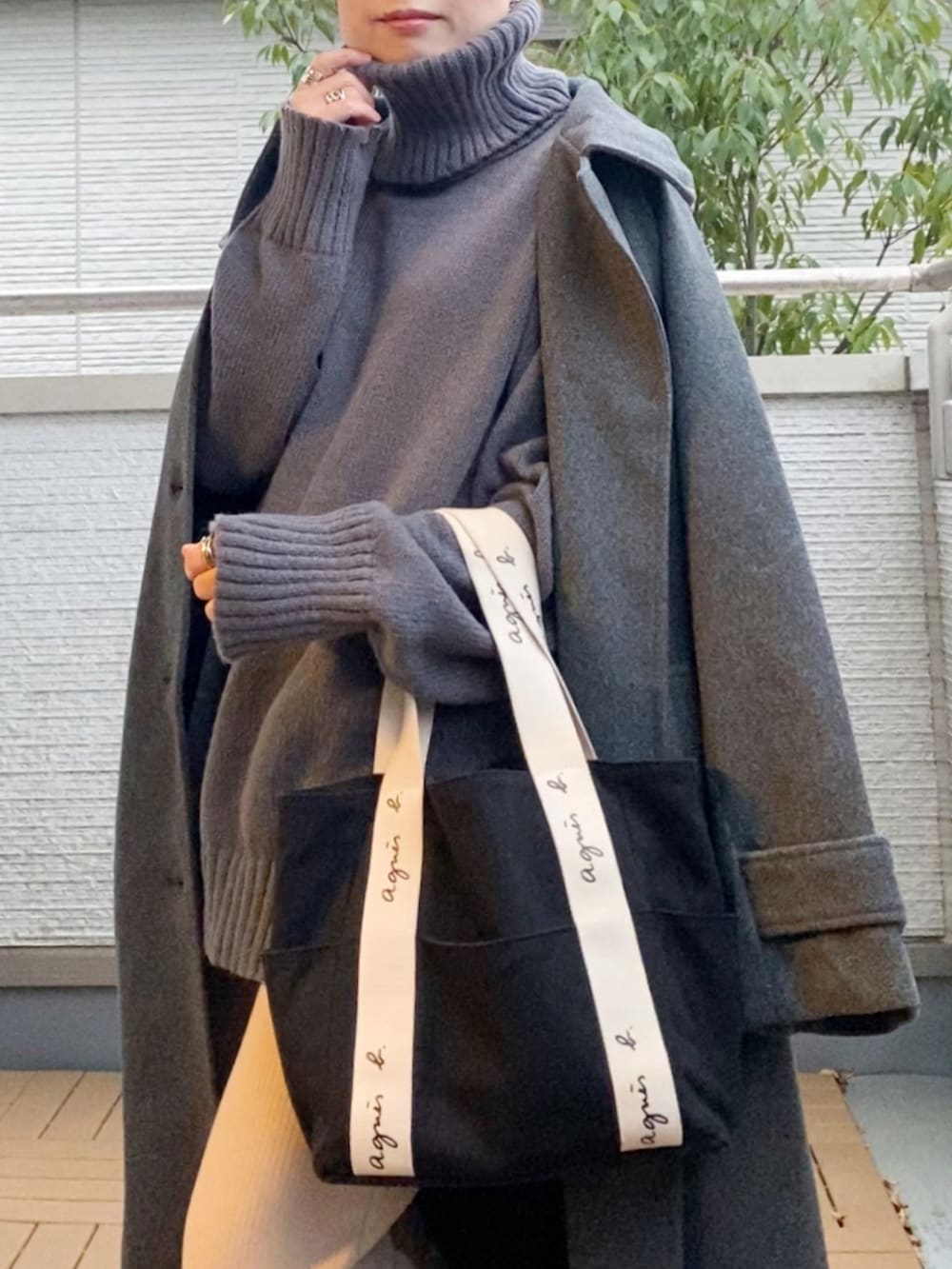 グレー系のステンカラーコート、グレー系のニット/セーター、ベージュ系のその他パンツを着用したレディースの冬コーディネートの4枚目の写真