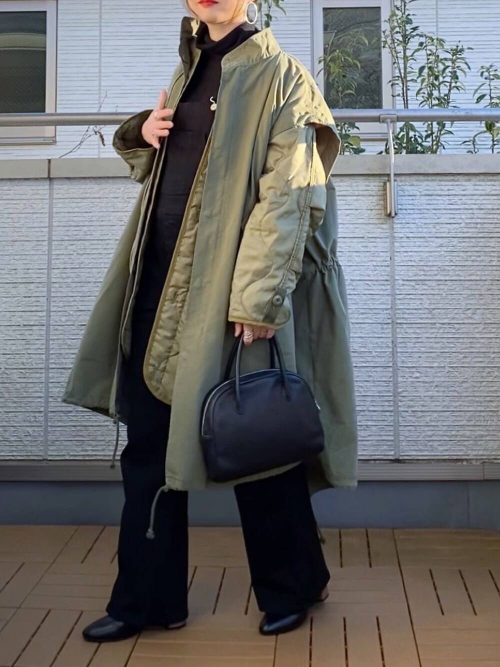 グリーン系のモッズコート、ブラック系のサロペット/オーバーオール、ブラック系のTシャツ/カットソーを着用したレディースの冬コーディネートの2枚目の写真