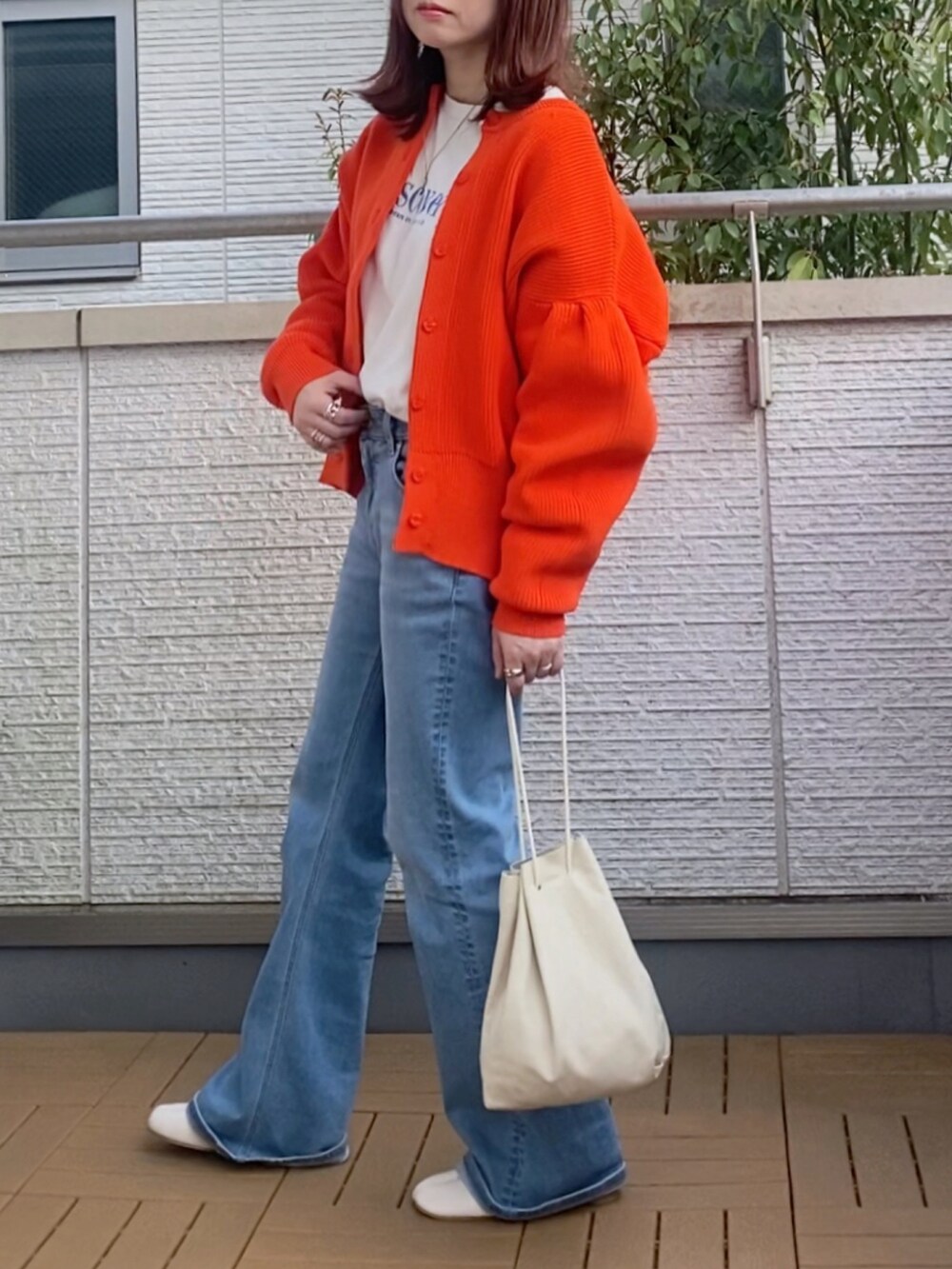オレンジ系のカーディガン/ボレロ、ホワイト系のTシャツ/カットソー、ブルー系のデニムパンツを着用したレディースの春コーディネートの2枚目の写真