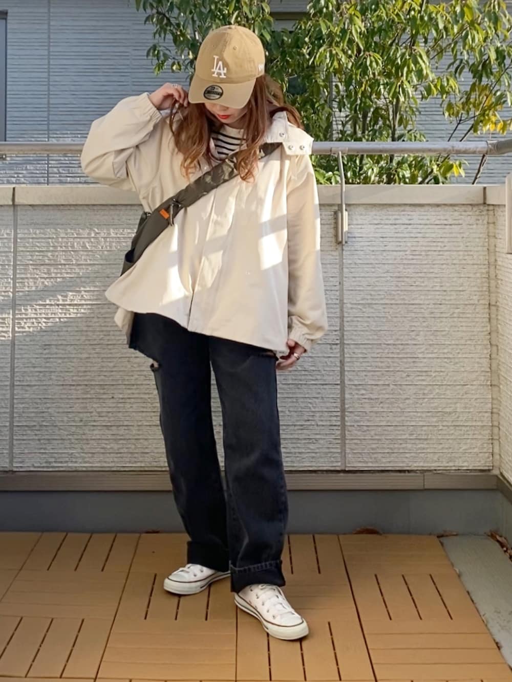 ホワイト系のマウンテンパーカー、ブラック系のTシャツ/カットソー、ブラック系のデニムパンツを着用したレディースの春コーディネートの3枚目の写真
