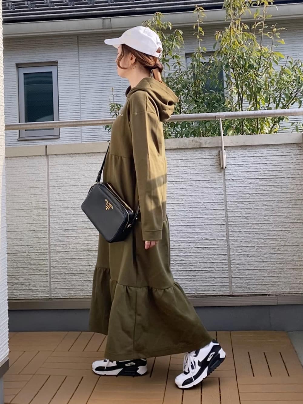 グリーン系のワンピース、ホワイト系のスニーカー、ホワイト系のキャップを着用したレディースの春コーディネートの2枚目の写真