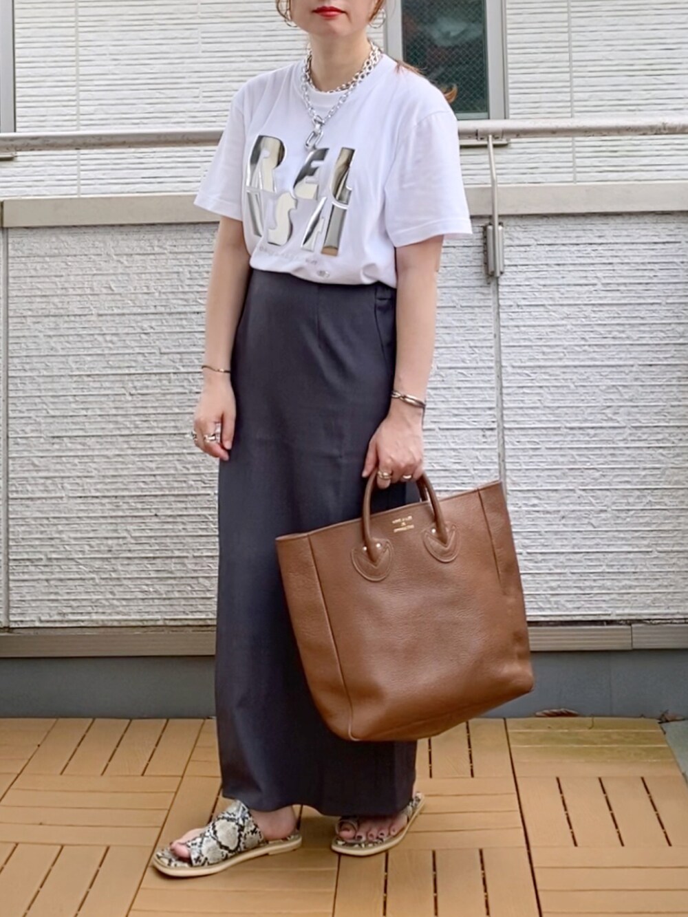 ホワイト系のTシャツ/カットソー、グレー系のスカート、ブラウン系のトートバッグを着用したレディースの夏コーディネートの2枚目の写真