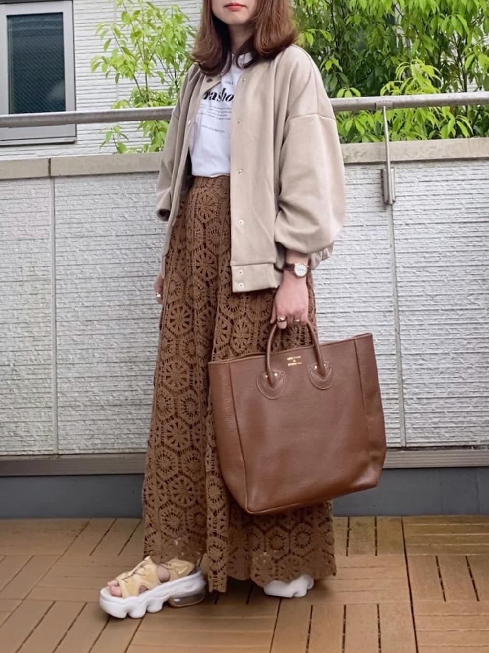 ベージュ系のスタジャン、ホワイト系のTシャツ/カットソー、ブラウン系のスカートを着用したレディースの春コーディネートの2枚目の写真