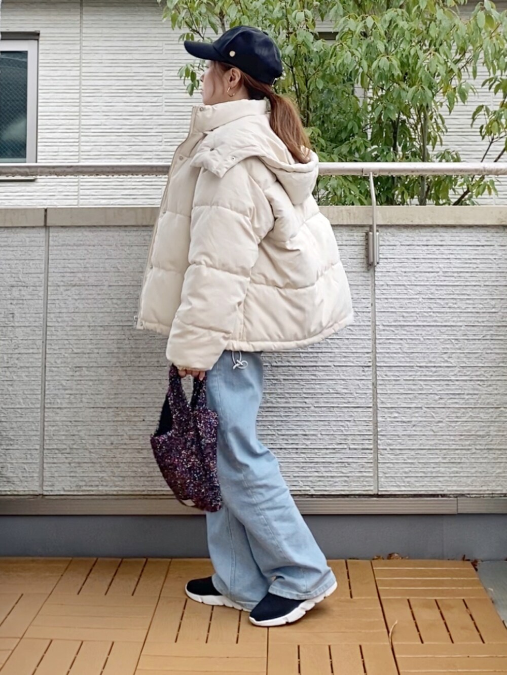 ホワイト系のダウンジャケット/コート、グレー系のニット/セーター、ブルー系のデニムパンツを着用したレディースの冬コーディネートの3枚目の写真