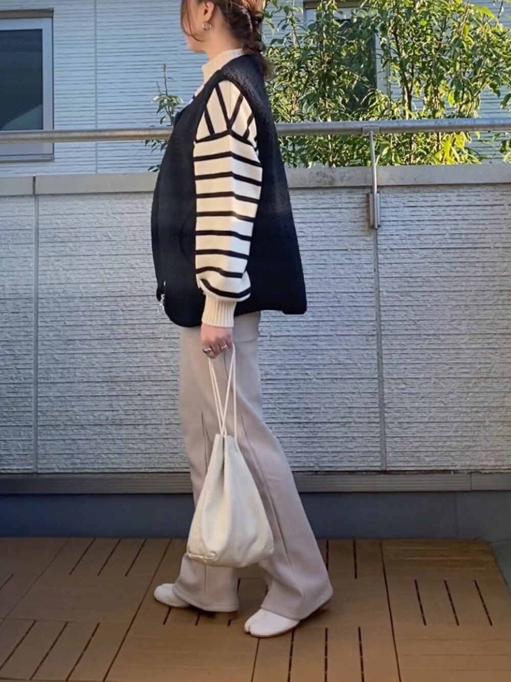 ホワイト系のニット/セーター、ブラック系のベスト、ベージュ系のその他パンツを着用したレディースの秋コーディネートの2枚目の写真