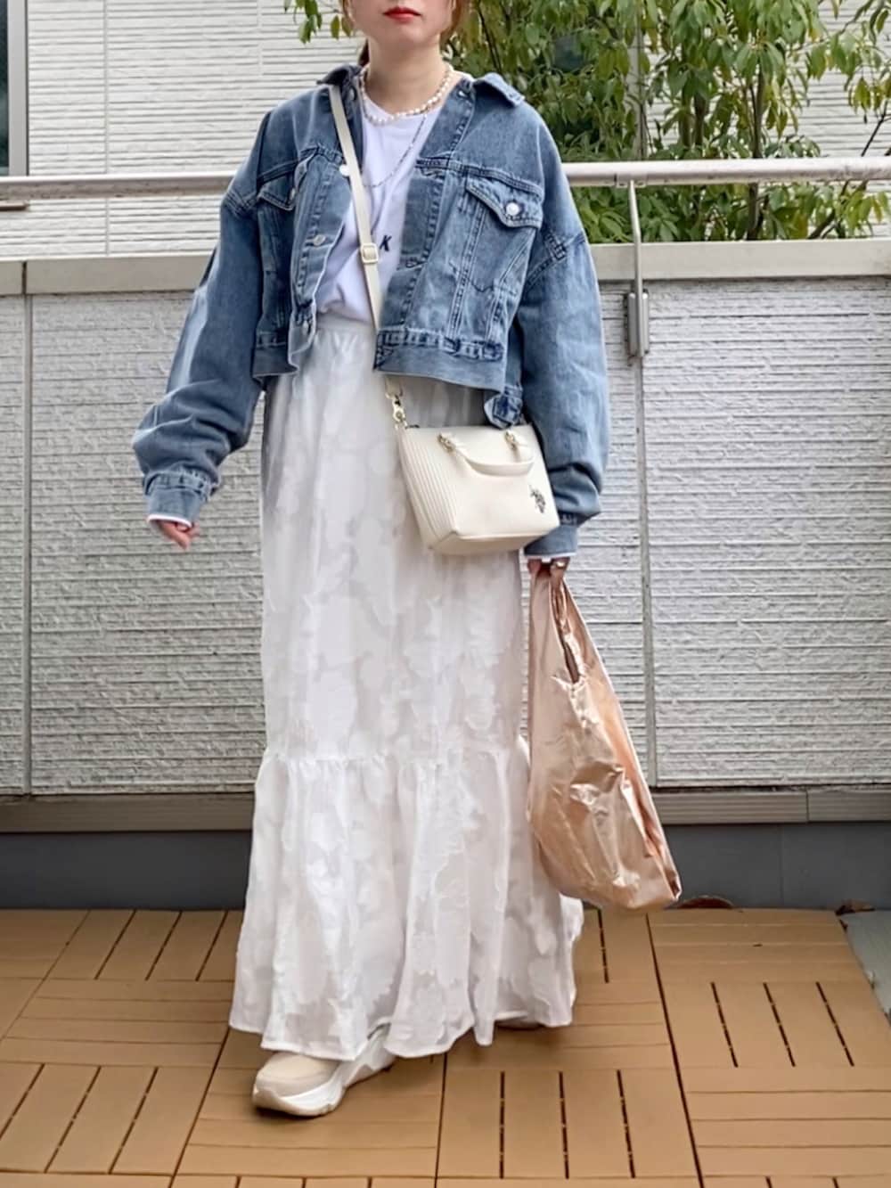 ブルー系のデニムジャケット、ホワイト系のスカート、ホワイト系のショルダーバッグを着用したレディースの春コーディネートの2枚目の写真