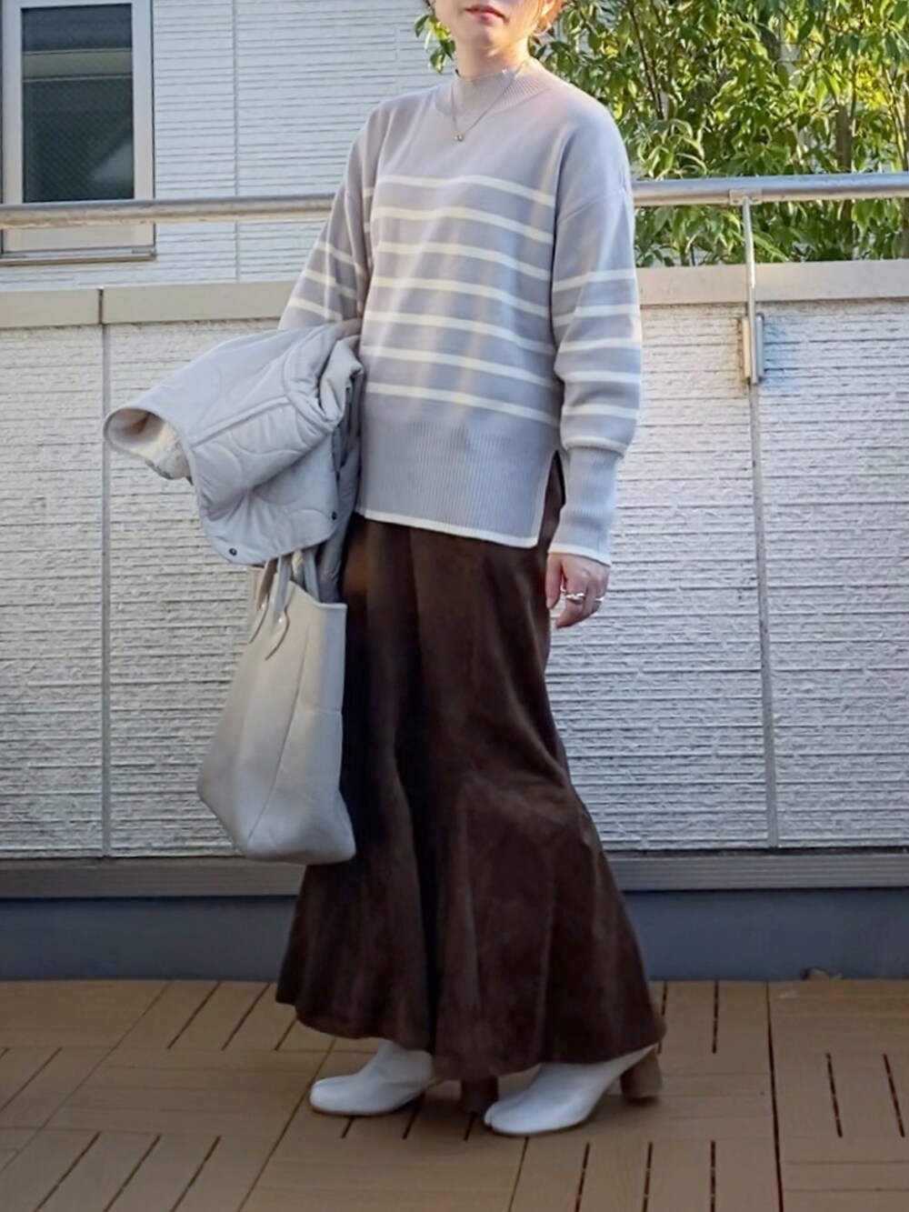ベージュ系のブルゾン、グレー系のニット/セーター、ブラウン系のスカートを着用したレディースの秋コーディネートの4枚目の写真