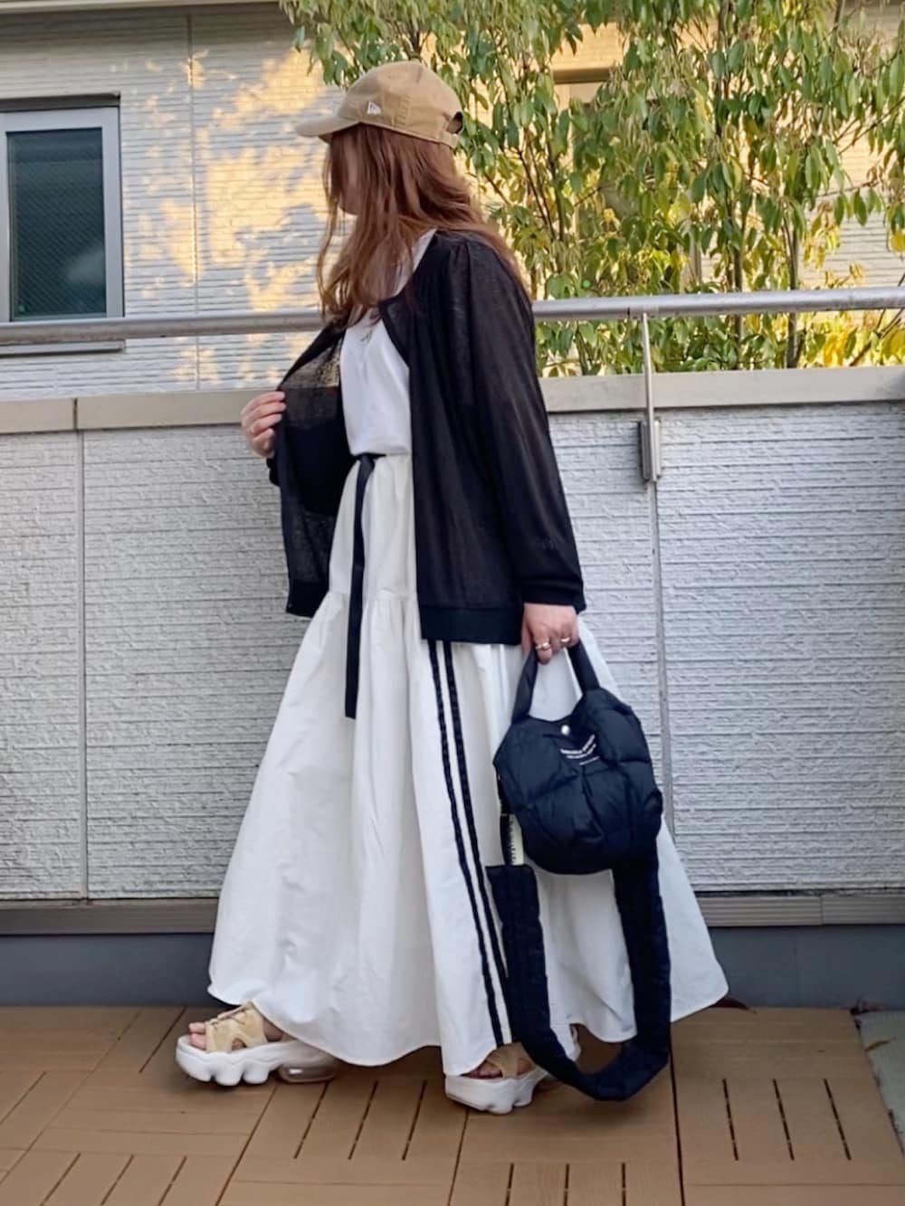 ブラック系のブルゾン、イエロー系のTシャツ/カットソー、ホワイト系のスカートを着用したレディースの春コーディネートの3枚目の写真