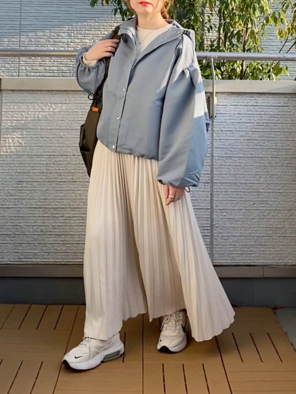 ブルー系のマウンテンパーカー、グリーン系のショルダーバッグ、ホワイト系のスニーカーを着用したレディースの春コーディネートの2枚目の写真