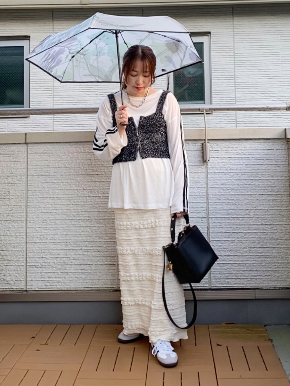 ブラック系のベスト、ホワイト系のTシャツ/カットソー、ホワイト系のスカートを着用したレディースの秋コーディネートの2枚目の写真