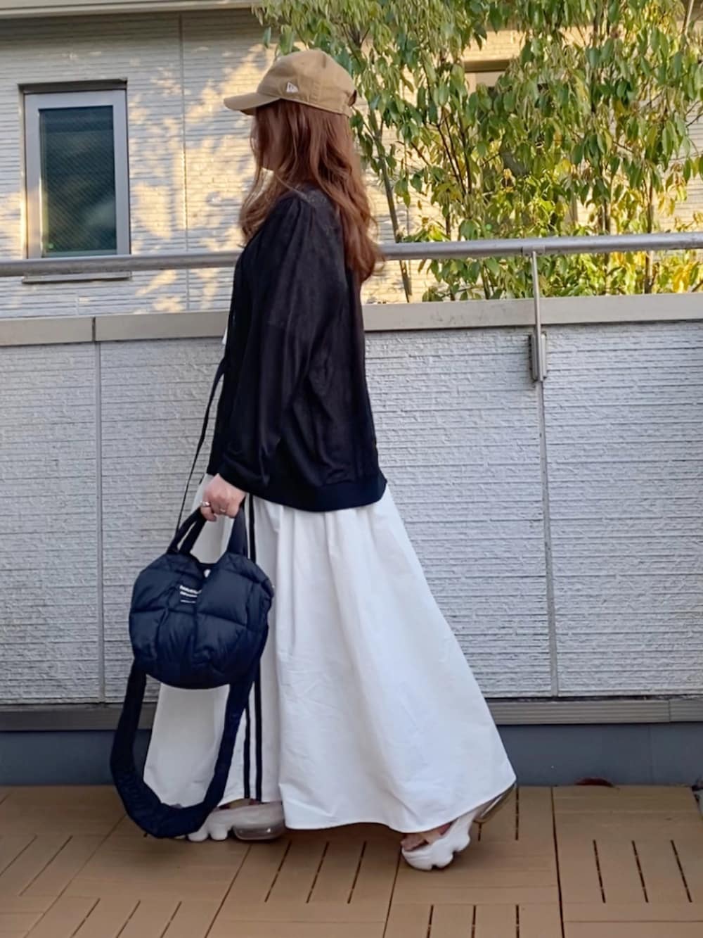 ブラック系のブルゾン、イエロー系のTシャツ/カットソー、ホワイト系のスカートを着用したレディースの春コーディネートの4枚目の写真